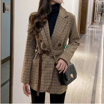 Women's houndstooth belted blazer worn with black trousers, full length