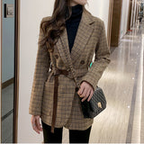 Women's houndstooth belted blazer worn with black trousers, full length