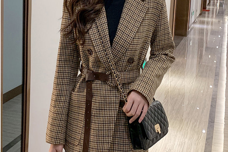Women's houndstooth belted blazer worn with black trousers, full length